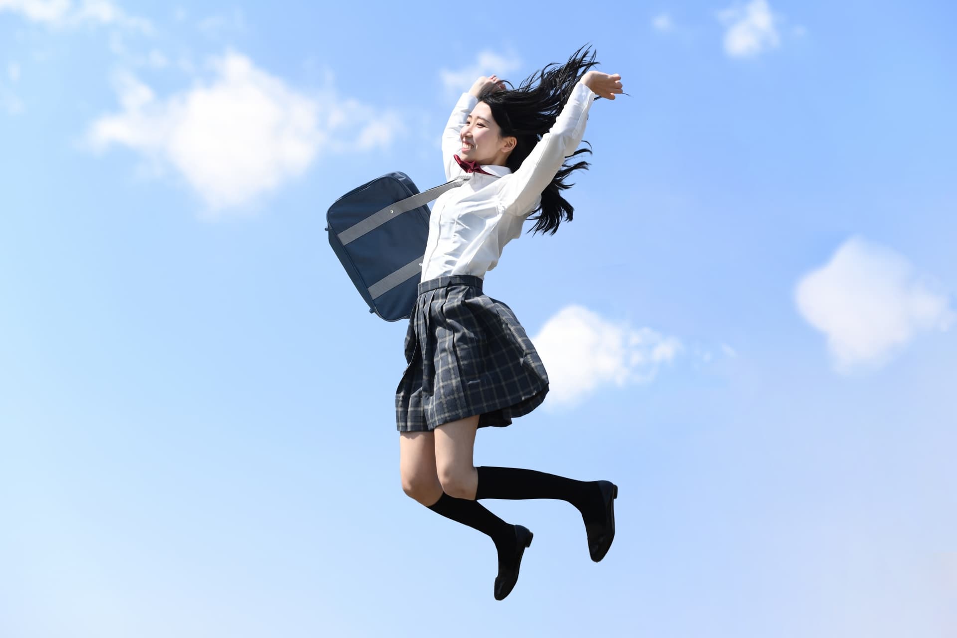 青空の下でジャンプする女子学生