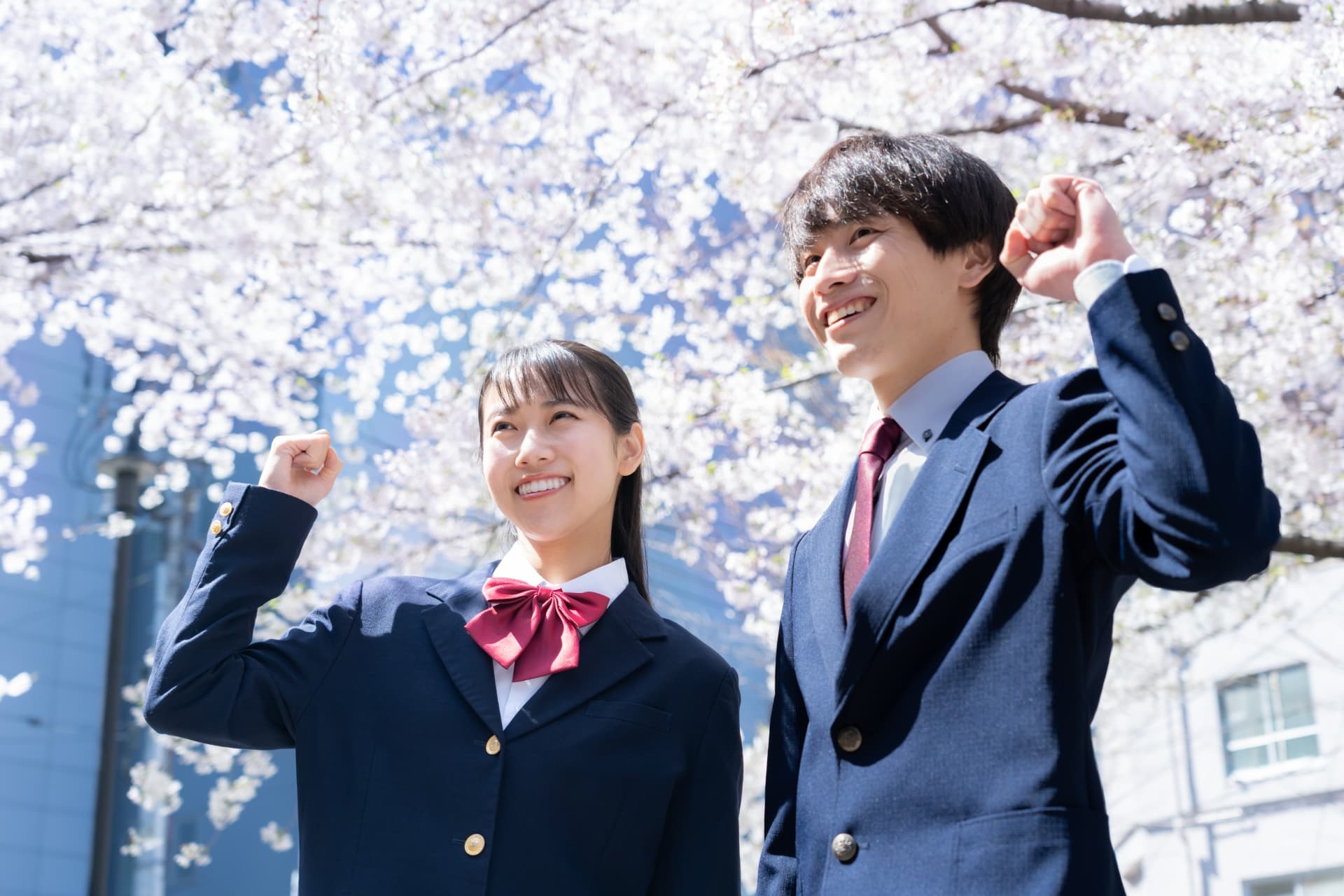 桜と拳を突き上げる学生